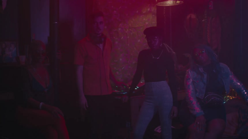 A dj poses with women in a hazy nightclub