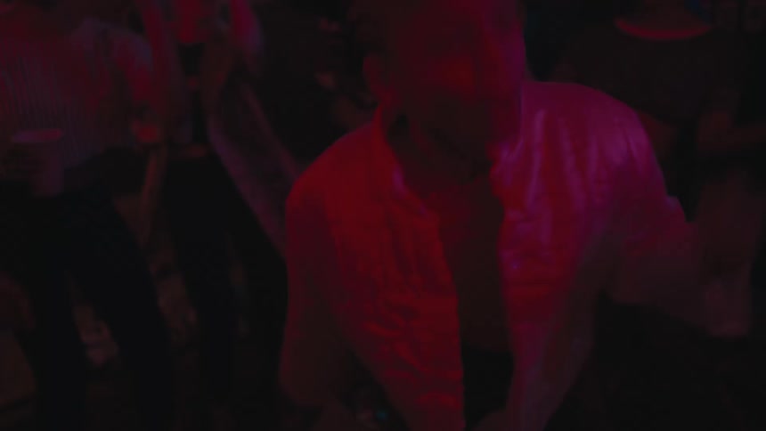 A woman at a night club dances in front of people as they dance and clap
