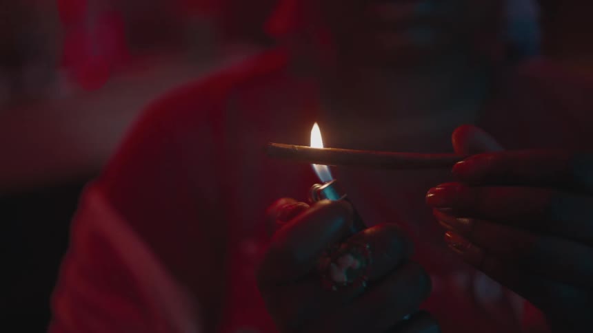 A woman is lighting up drugs in the dark
