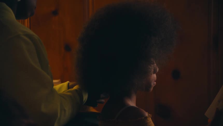 A woman plays with her daughters hair as they sit in the living room