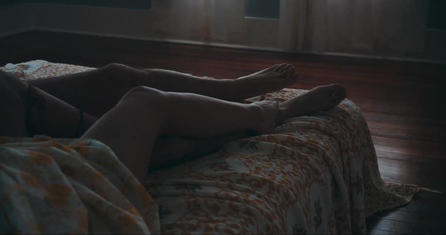 A couple intertwine their legs together while lying in bed