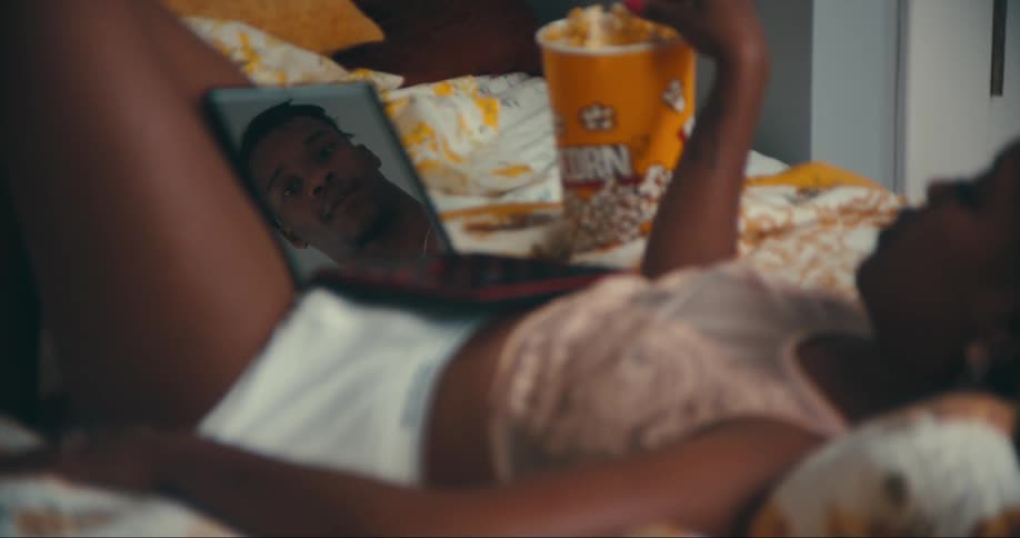 Woman eats popcorn as she lies down with open makeup case that reflects a man