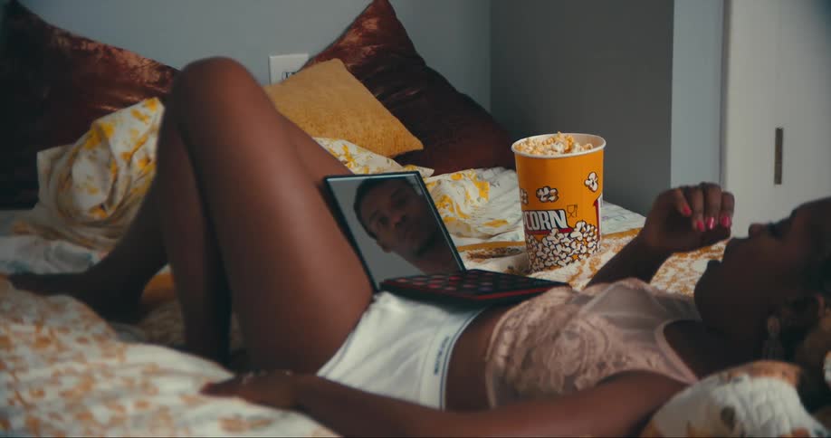 A woman eats popcorn with a mirror reflecting a mans face