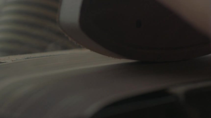 A sanding belt is working on a piece of wood