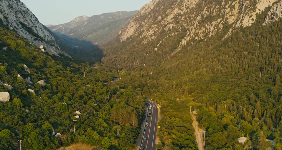 Heavy traffic drives down a highway that runs between steep mountains