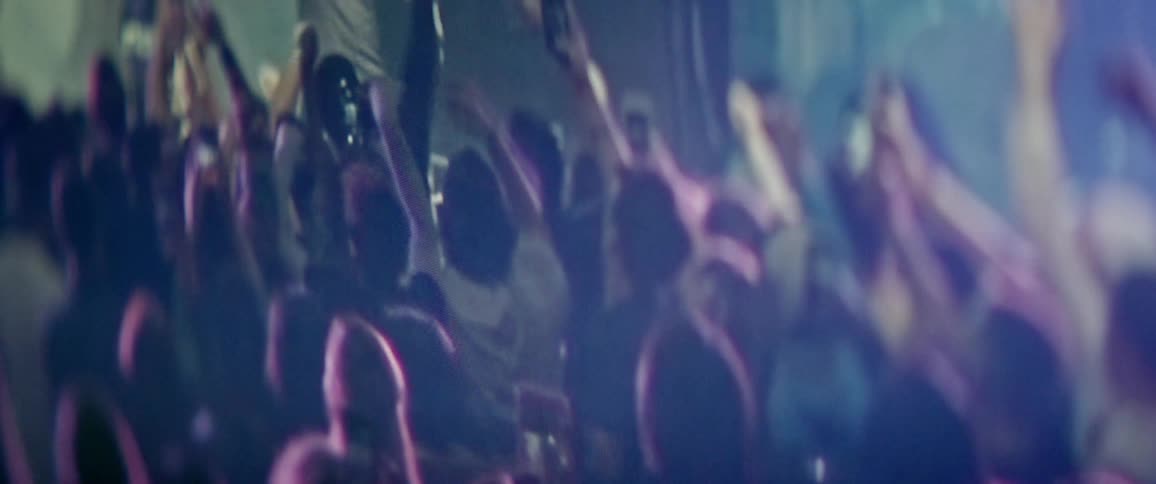 A crowd jumps up and down with arms raised at a concert