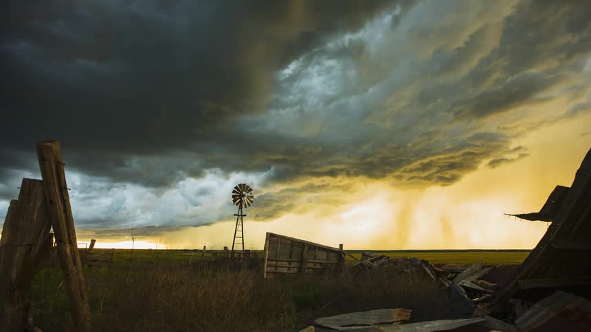 Dark clouds move over a rural area covering a yellow sky