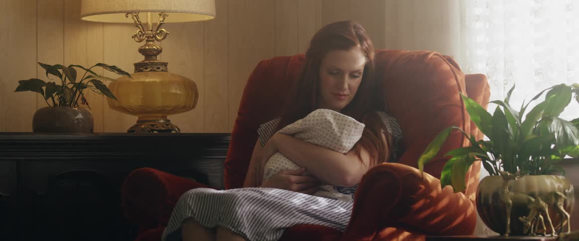 A mom rocking in a chair holding her baby and gazing at him with love