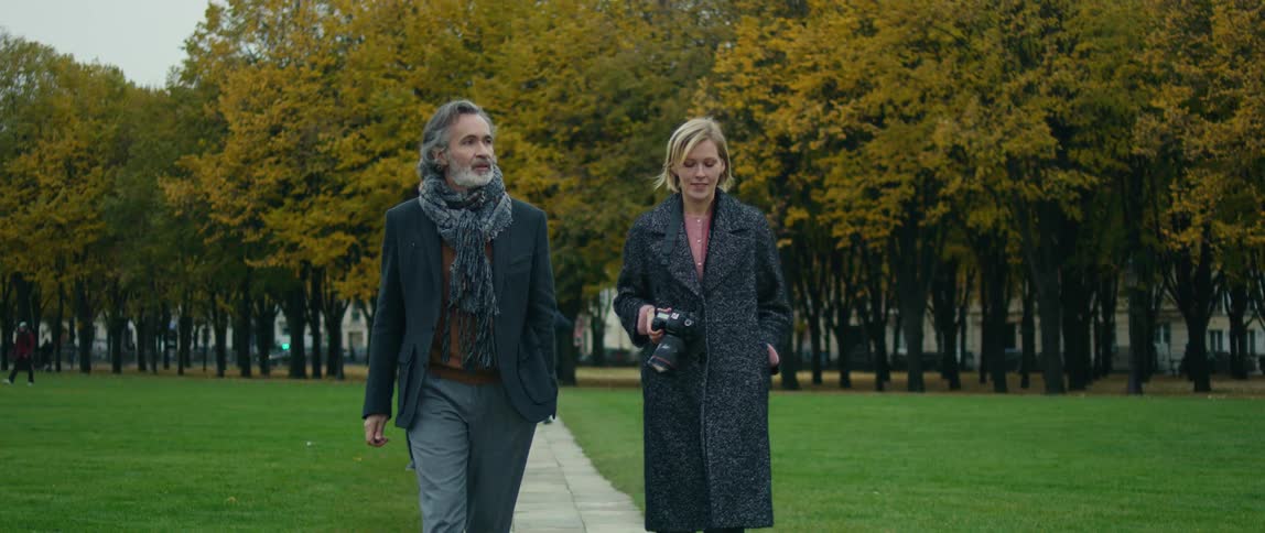 A man and woman walk down a paved path in a park