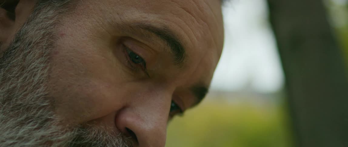 The face of a man sitting outside looking down