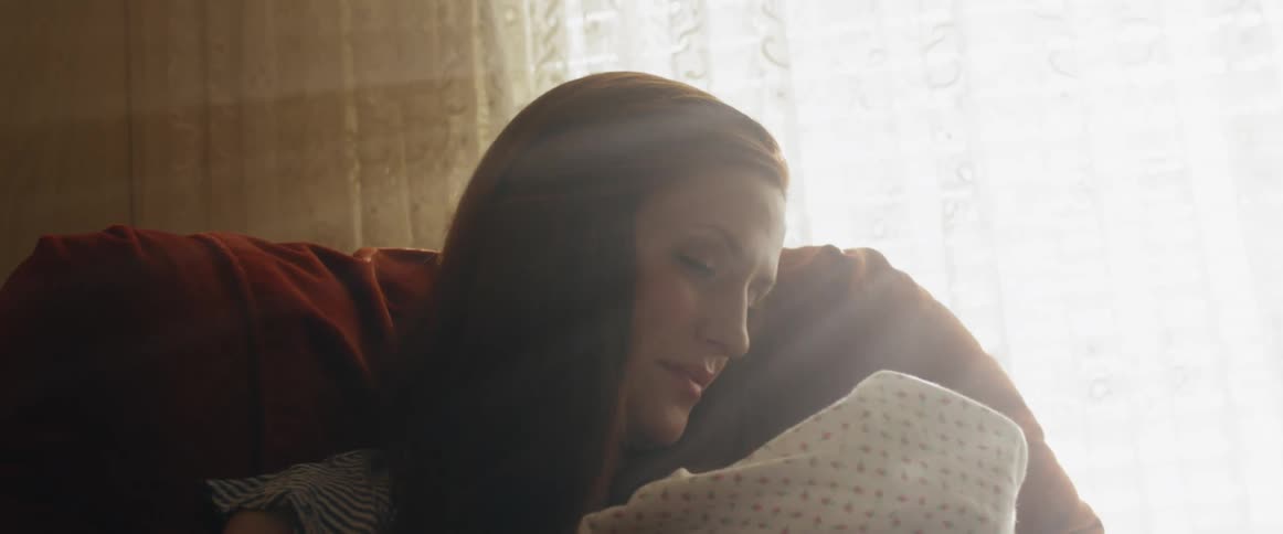 A mother is cradling her baby at home