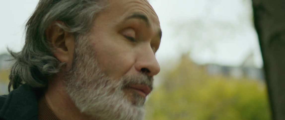 A man outside in a garden glancing up then back down