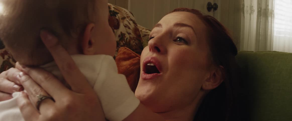 Mother lies on her back with her baby on her chest smiling and talking as she blows air