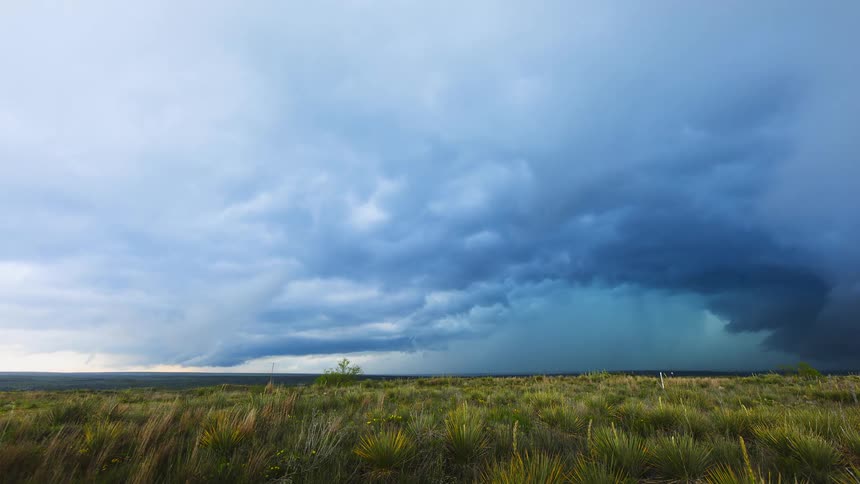 Storm clouds gather and move across green grass plains