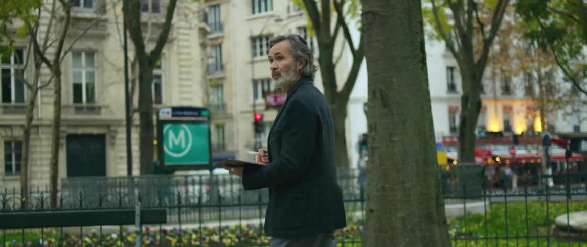 A man walks through a city park with his tablet