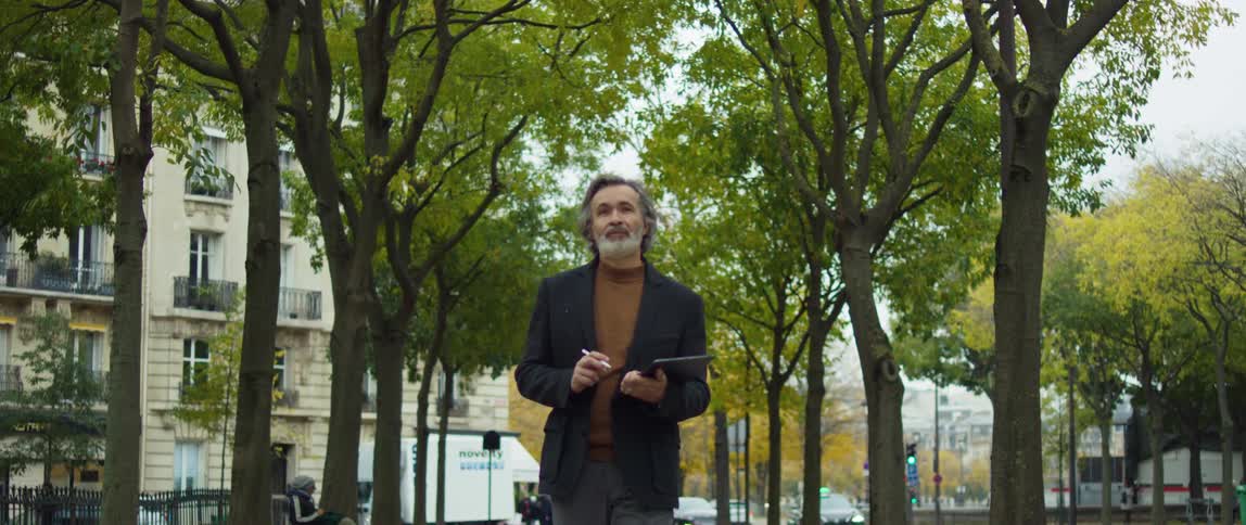A man walking in a city park drawing and tapping on a tablet with a stylus