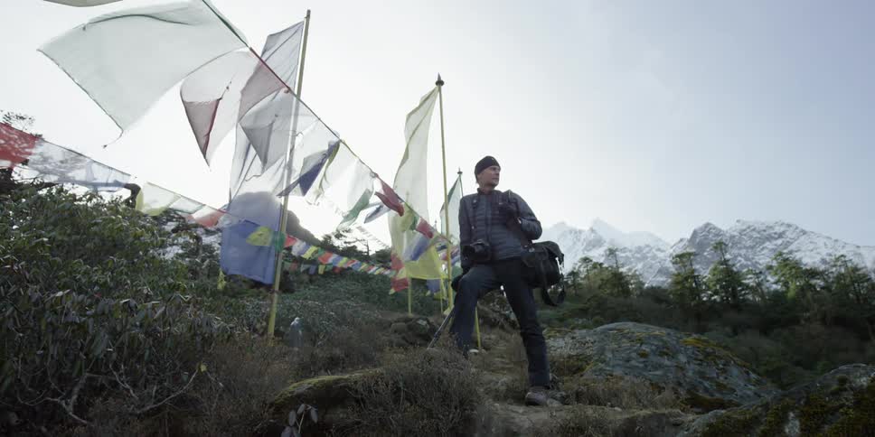 A man stands near a line of flags