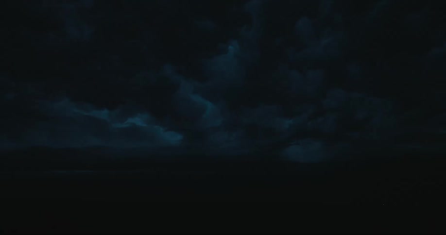 Lightning flashes from dark gray storm clouds at night