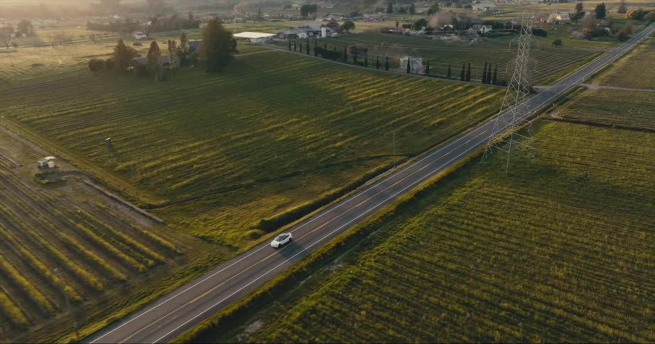 Car is driving on a road in a rural area at dusk
