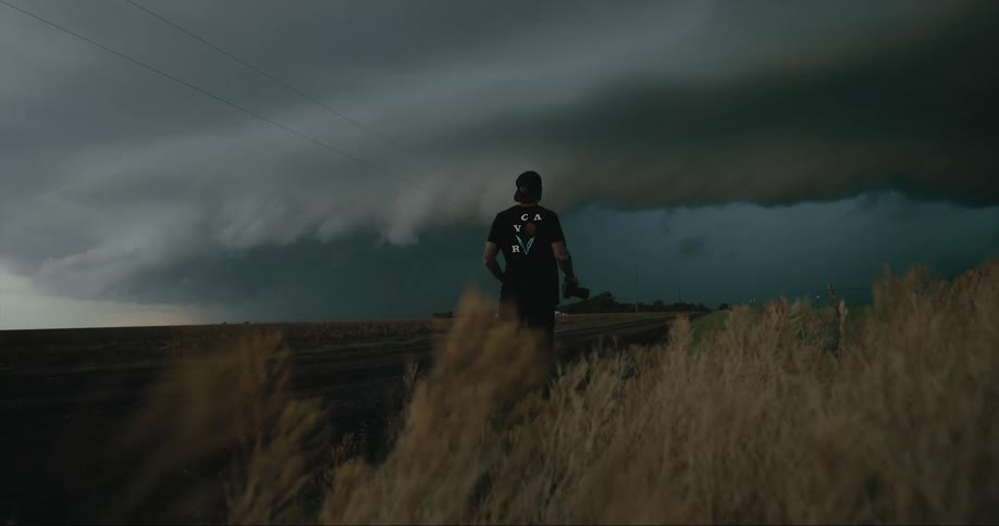 The silhouette of a male photographer can be seen as he watches massive storm clouds gather in the sky