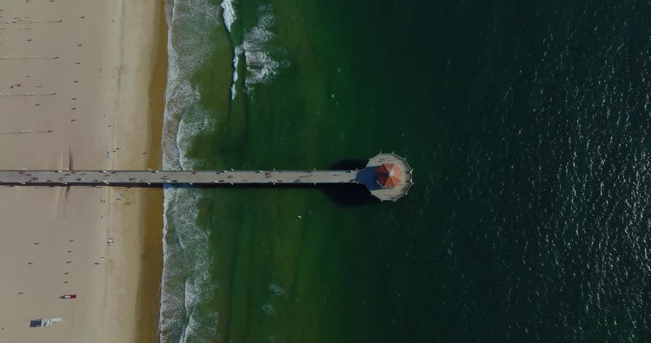 A long pier that juts out over the ocean has a single building standing at the very end