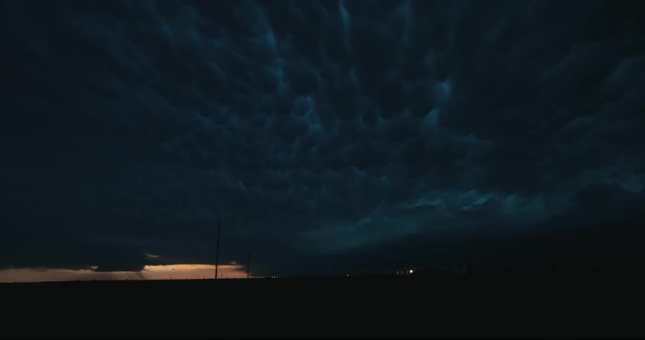 Dark storm clouds and a flash of lightning over a rural area