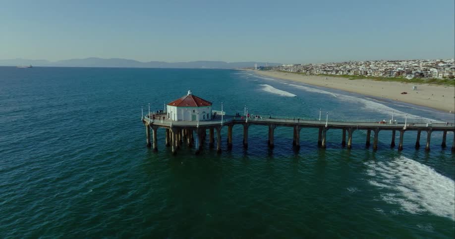 A single rounded building stands atop the end of a long pier that sticks out over the ocean