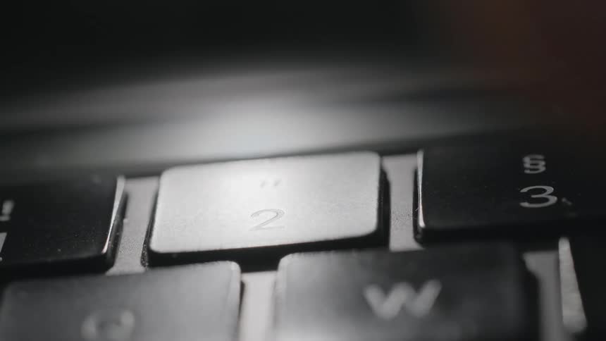 A person presses a number key on a computer keyboard with their finger