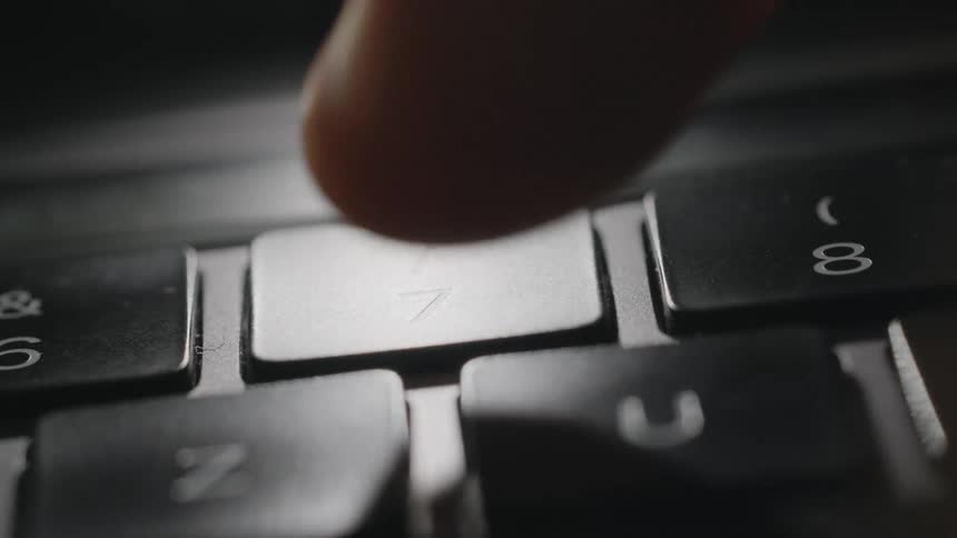 A person uses their finger to press a number key on a keyboard