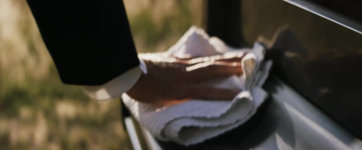 A man wiping an outdoor piano clean with a towel