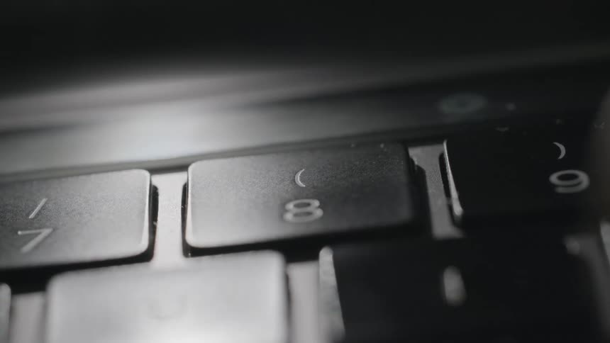 A finger pressing the eight button on a keyboard