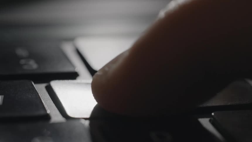 A finger presses the e key on a laptop keyboard