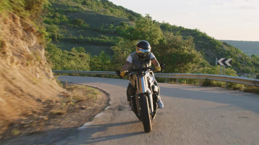 A man rides his motorcycle down a curvy mountain road