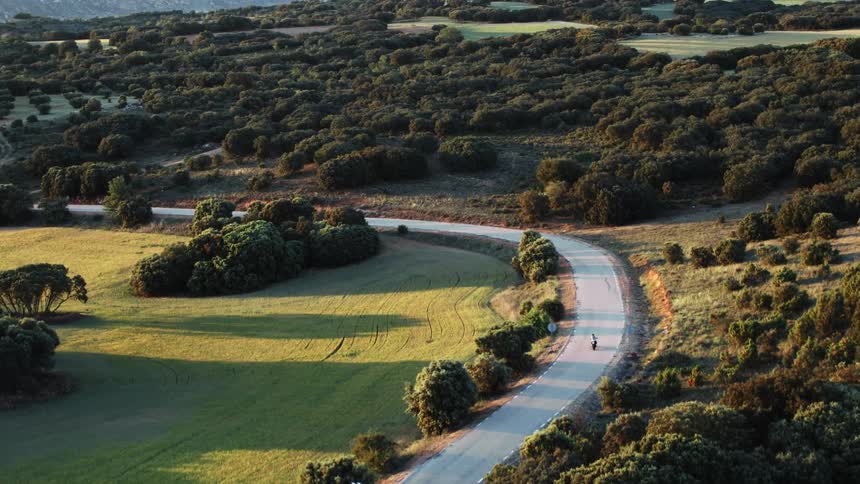 A motorcyclist rides down a curvy rural highway