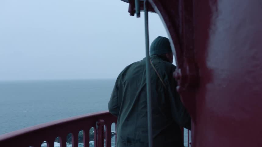 A man walks onto his balcony overlooking the sea