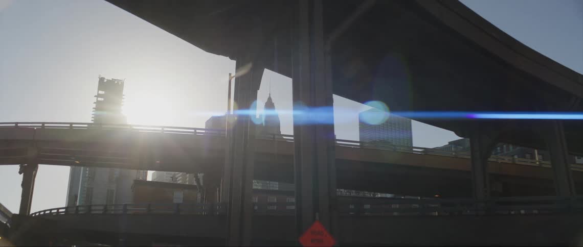 City skyscrapers visible behind highway on and off ramps on a bright sunny day