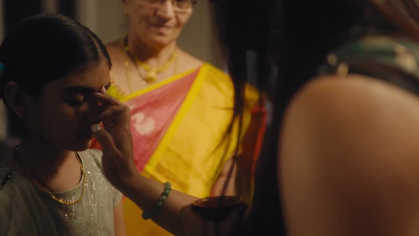 A woman places a bindi on a young girl