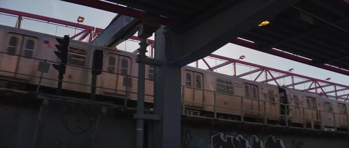 The sun shines brightly as a train travels across a bridge