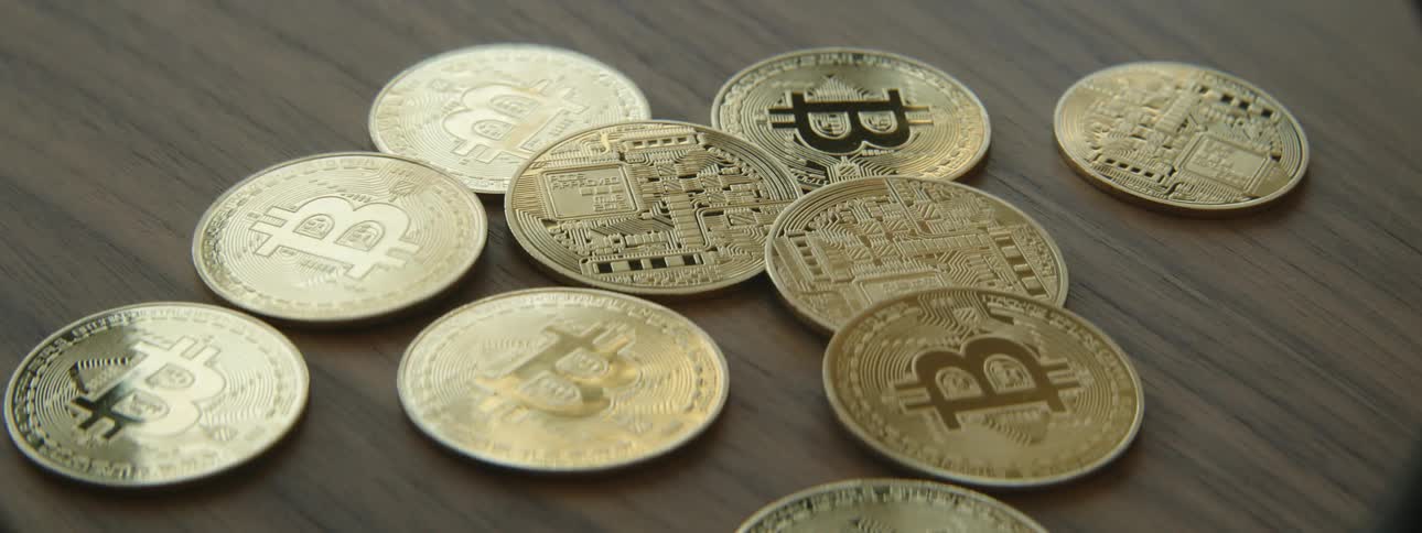 Gold commemorative bitcoin coins are dropped on a table