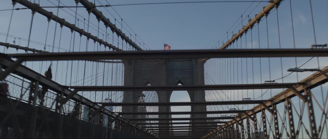 A large bridge with people walking on it in front of office buildings in the skyline