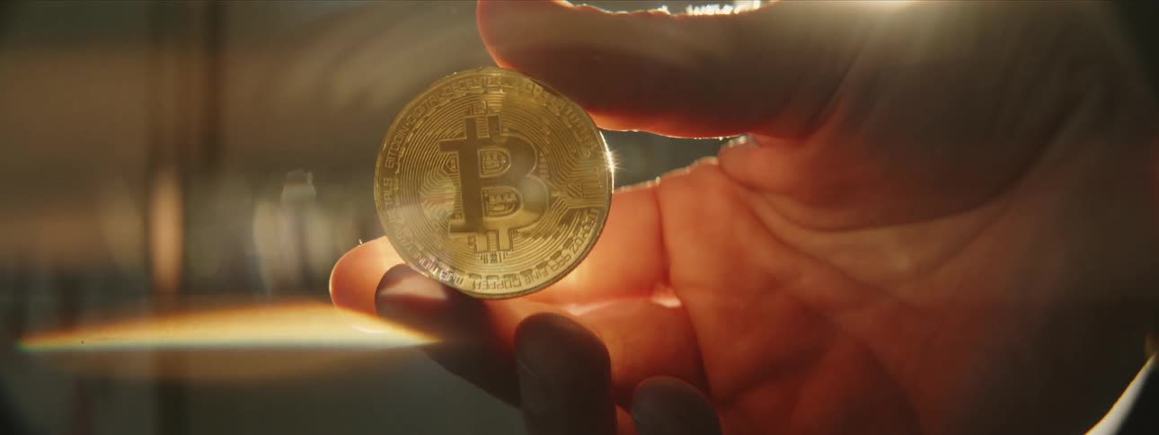 Hand holds bitcoin as the sun shines brightly