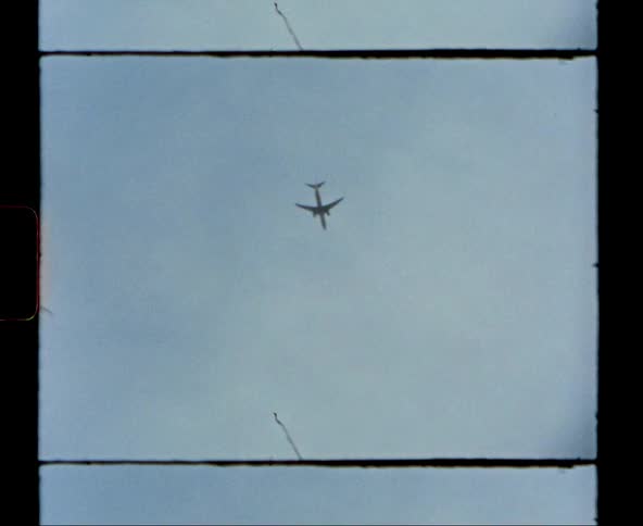 A large commercial passenger airplane flies overhead on a cloudy day