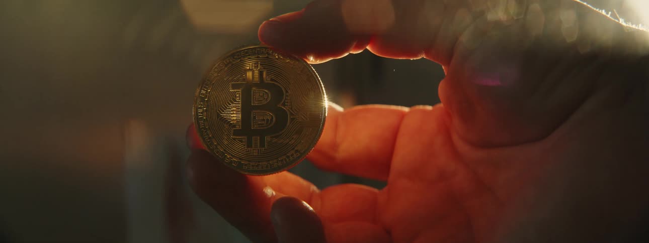 Man holds bitcoin in his hand while the sun shining