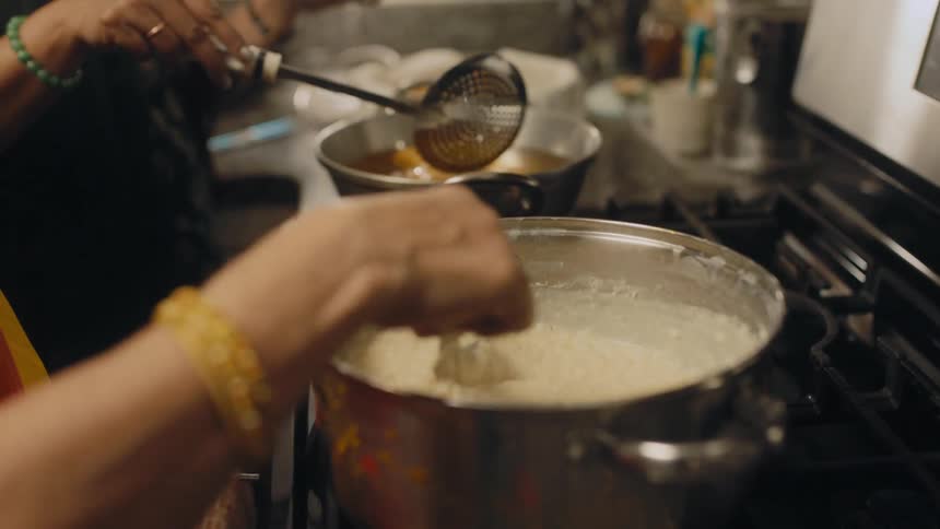 A pair of women cook on an oven side by side in a home kitchen
