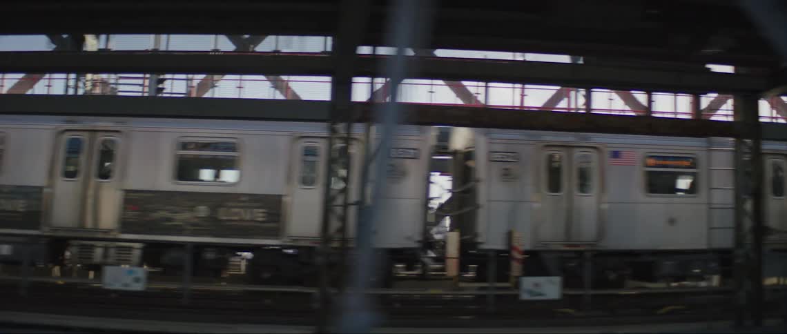Cars and a train traveling over an urban bridge with skyscrapers in the distance