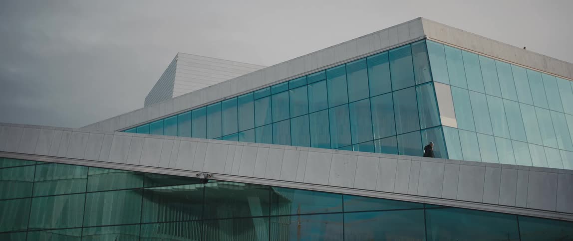 Two people walking down the ramp of the Norwegian National Opera and Ballet House in Oslo, Norway.