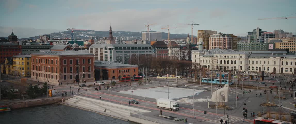 View of a downtown city square in Oslo, Norway with foot and vehicular traffic moving around an area under construction.