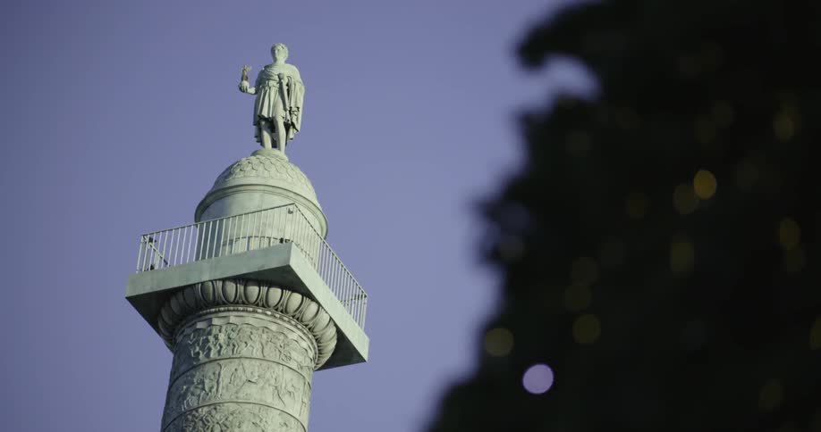 Statue standing on a tall tower against a clear blue sky