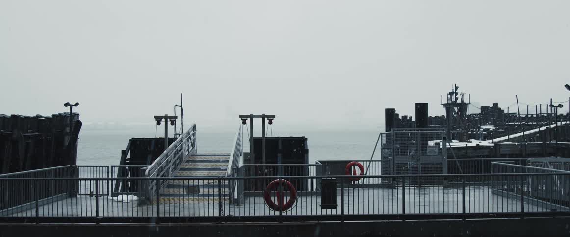 Steps on a the dock of an empty ferry slip on a foggy cloudy snowy day