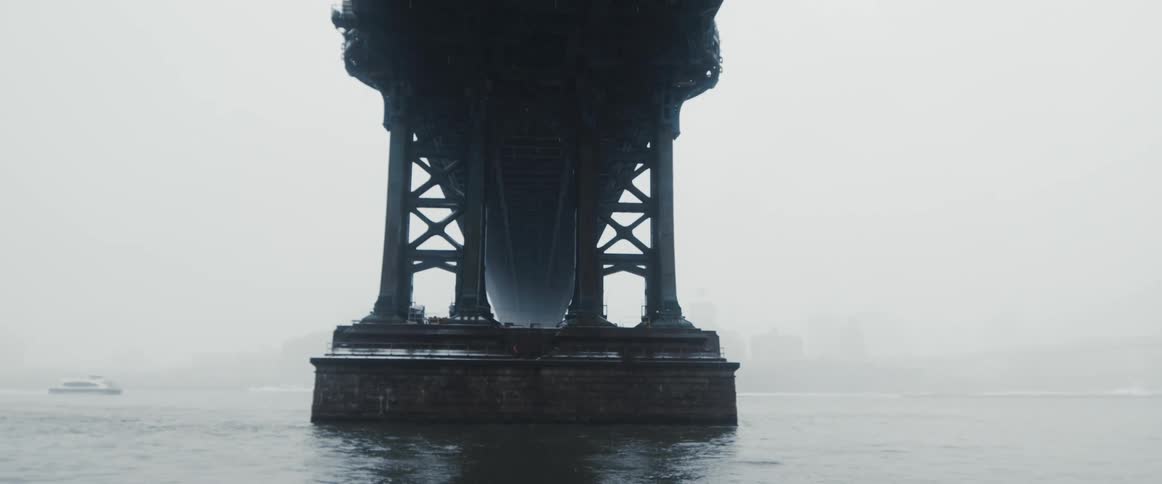 A large bridge across a vast waterway on a foggy day